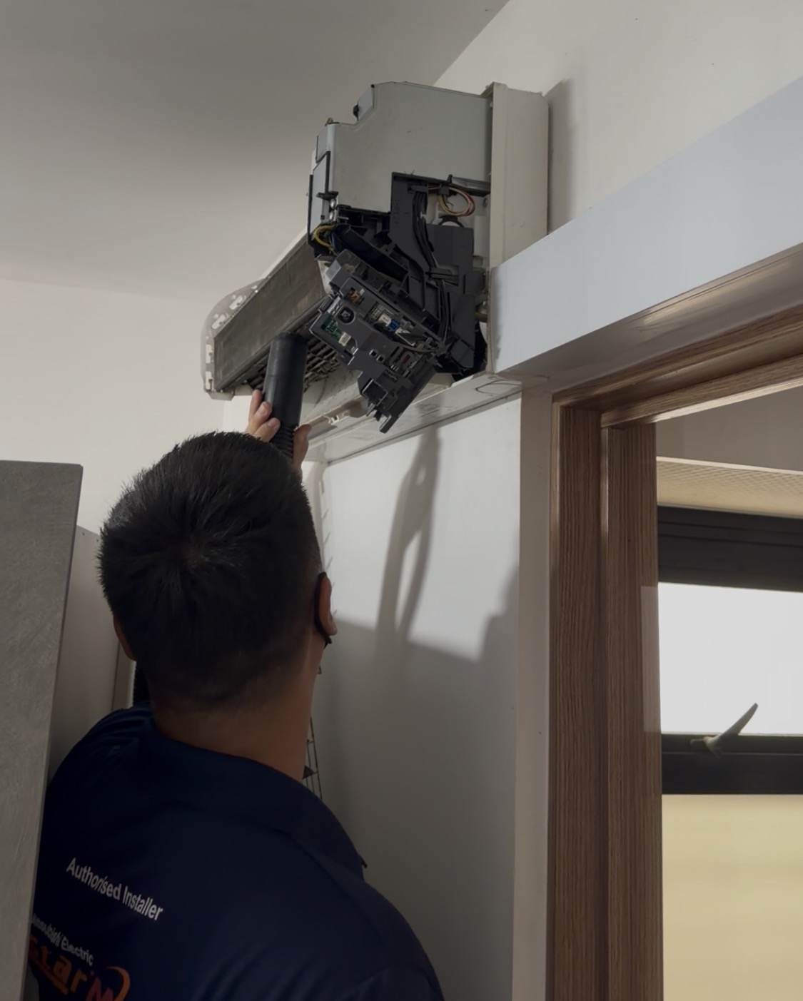Technician vacuuming an opened indoor aircon unit
