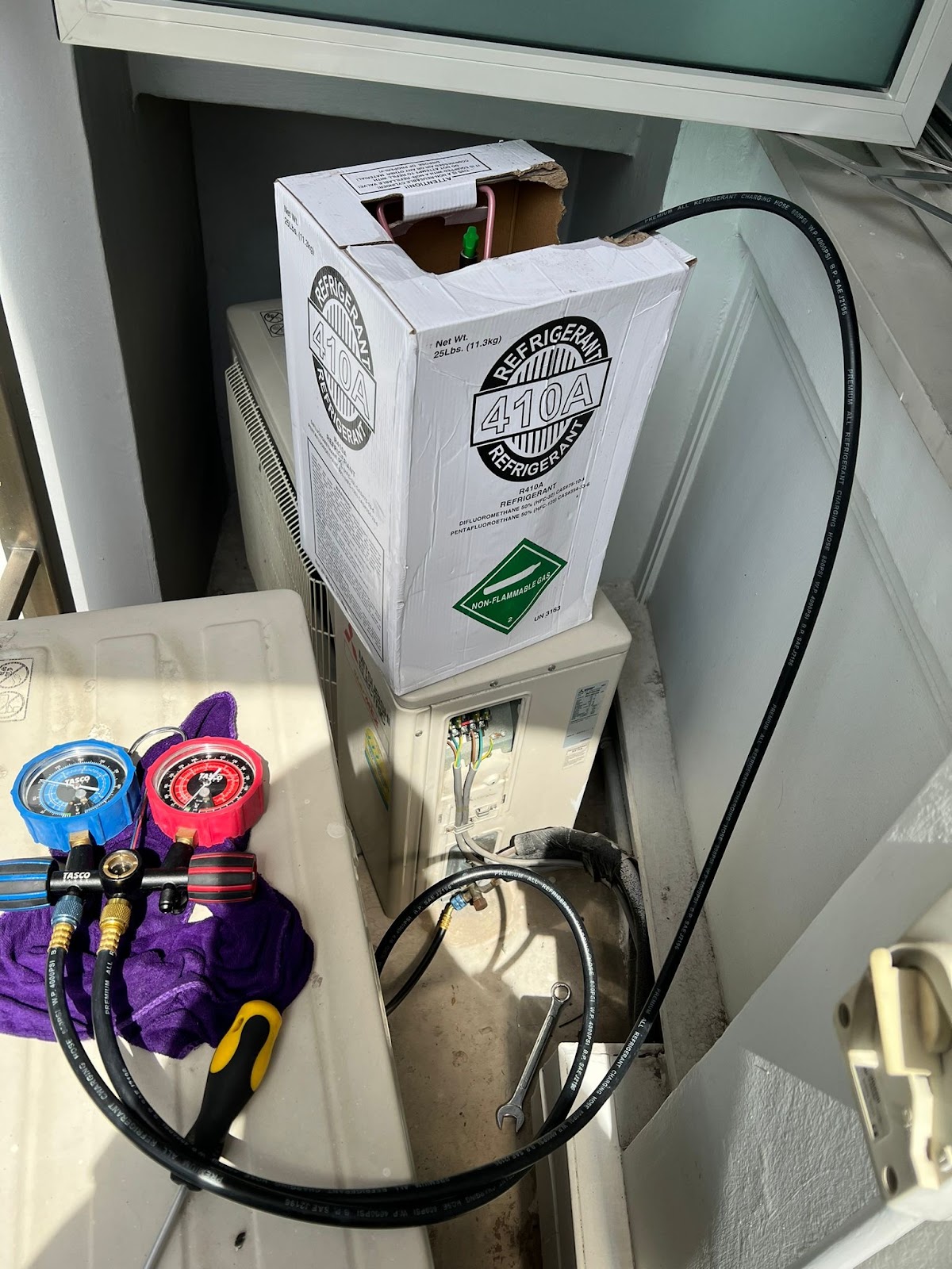 R410A refrigerant cylinder and gauges during a gas top-up